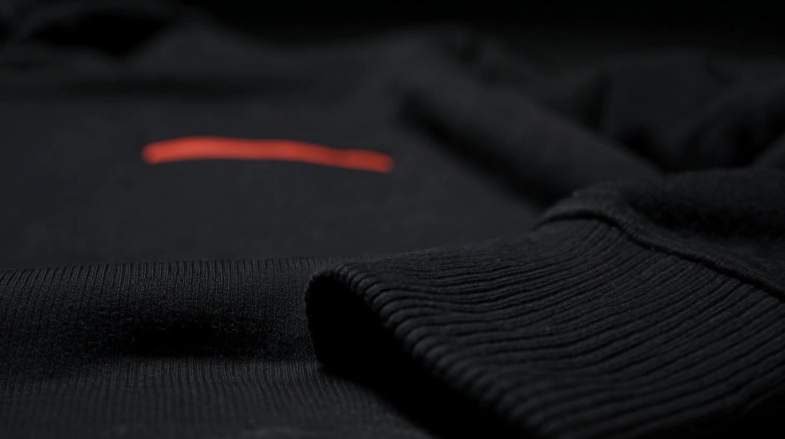 Close view of a heavyweight black hoodie under a single cold light